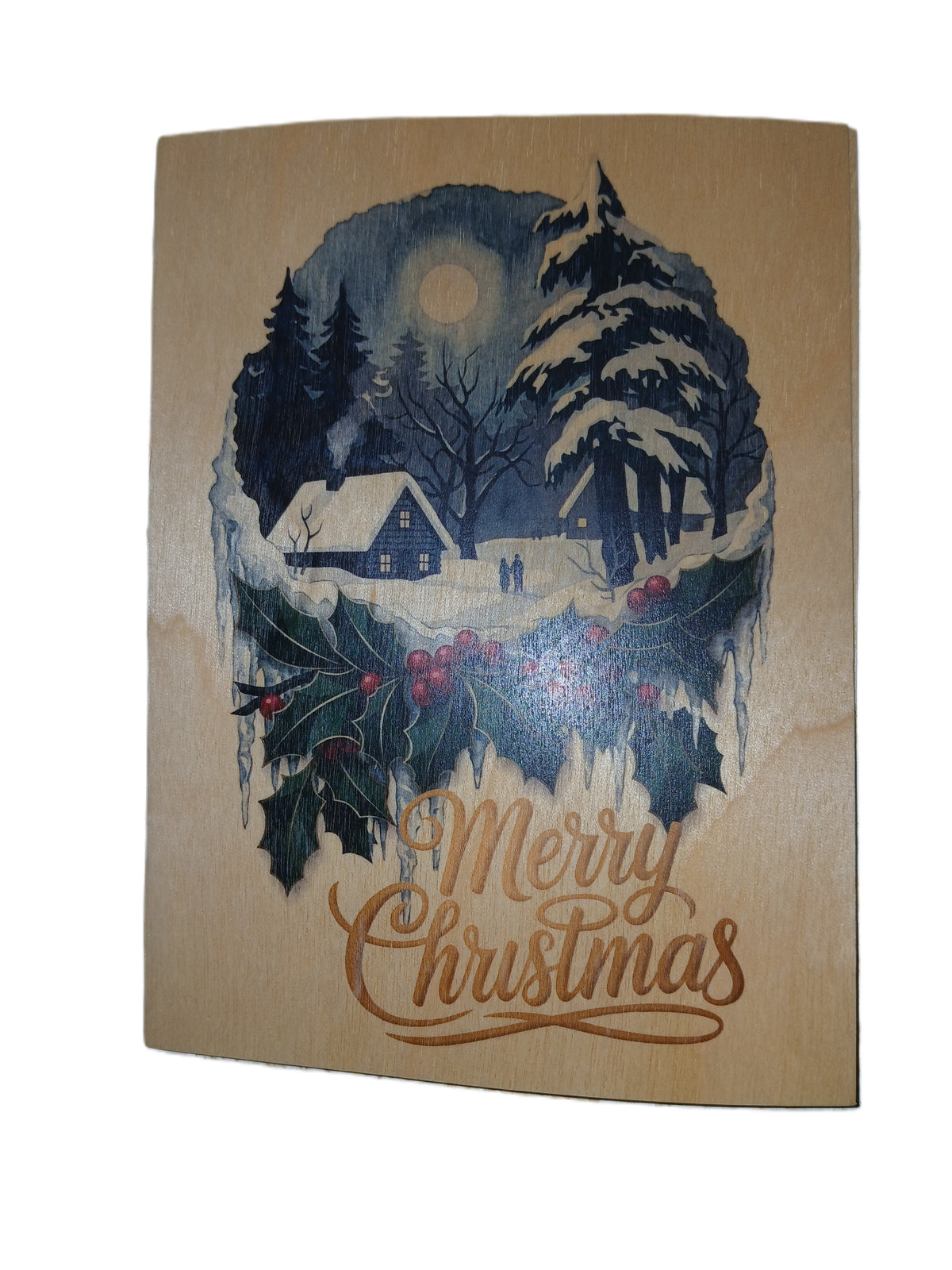 A rectangular wooden Christmas card featuring a winter scene with snow-covered trees, a small cabin, a full moon, holly, and the words 'Merry Christmas' in brown script on a light wood background.